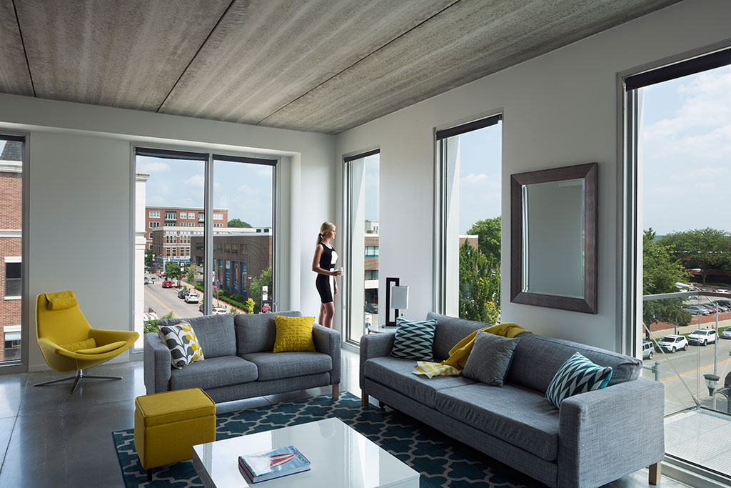 Interior image of a model apartment. modern, comfortable furniture fills the room with an open balcony door letting in the warm sunlight.